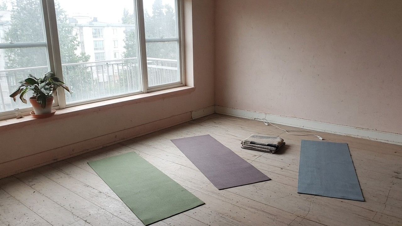 Three mats on a scuffed timber floor beside a blown-out window